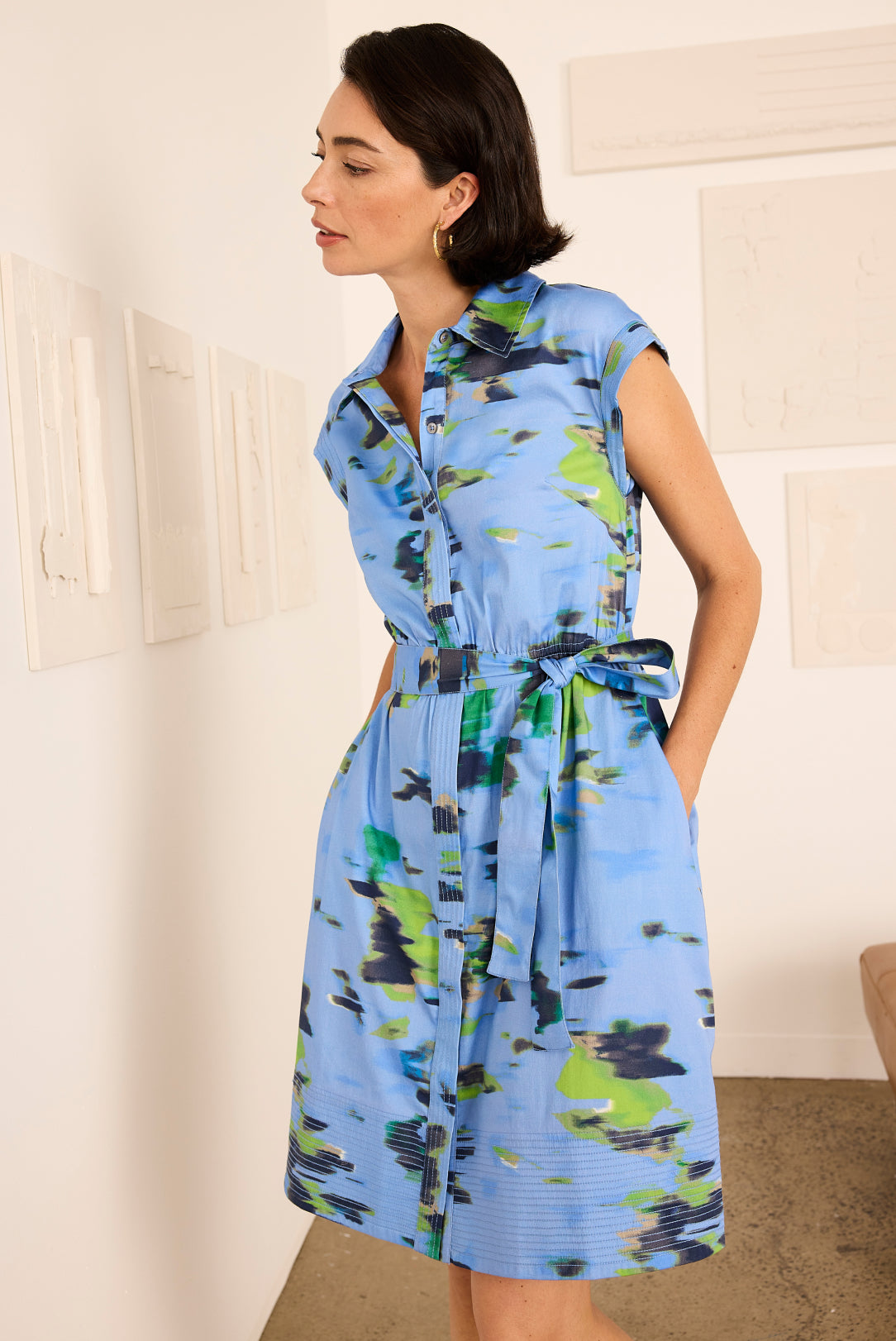 Woman wearing a blue floral dress in a room with white walls.