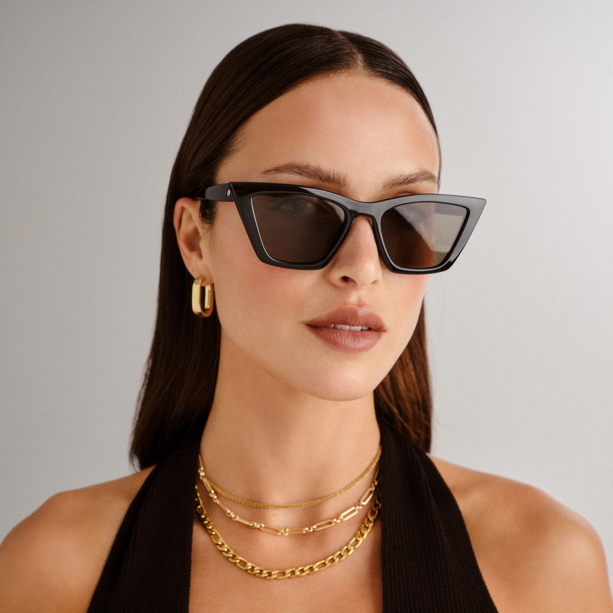 A model wears chic black cat eye sunglasses with bold angular frames and dark lenses for a sophisticated look.