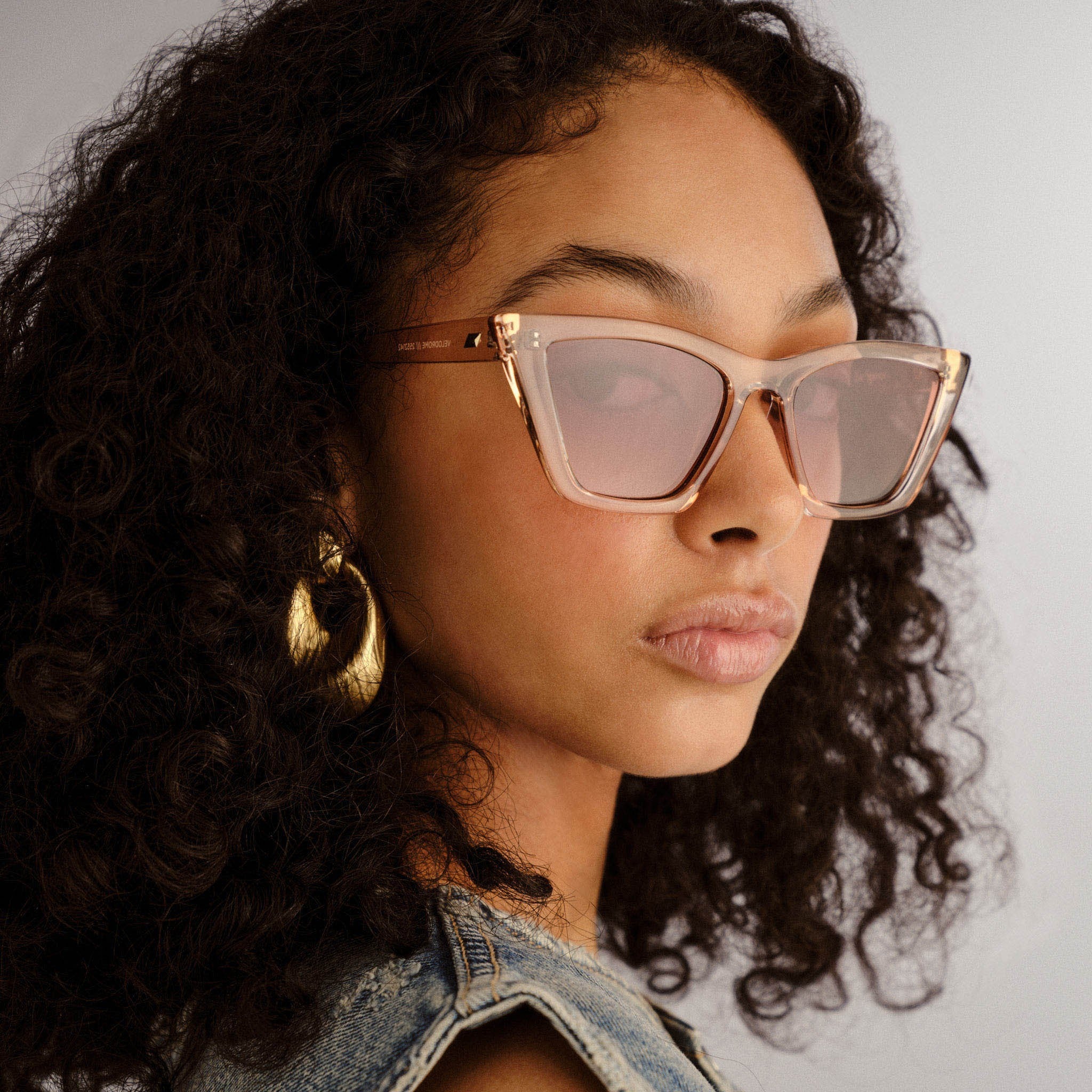 Translucent blush pink angular sunglasses with rose-tinted lenses and subtle gold hardware on the temples.