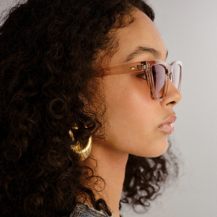 Translucent light brown chunky rectangular frames with brown tinted lenses and gold temple accents, worn in profile.