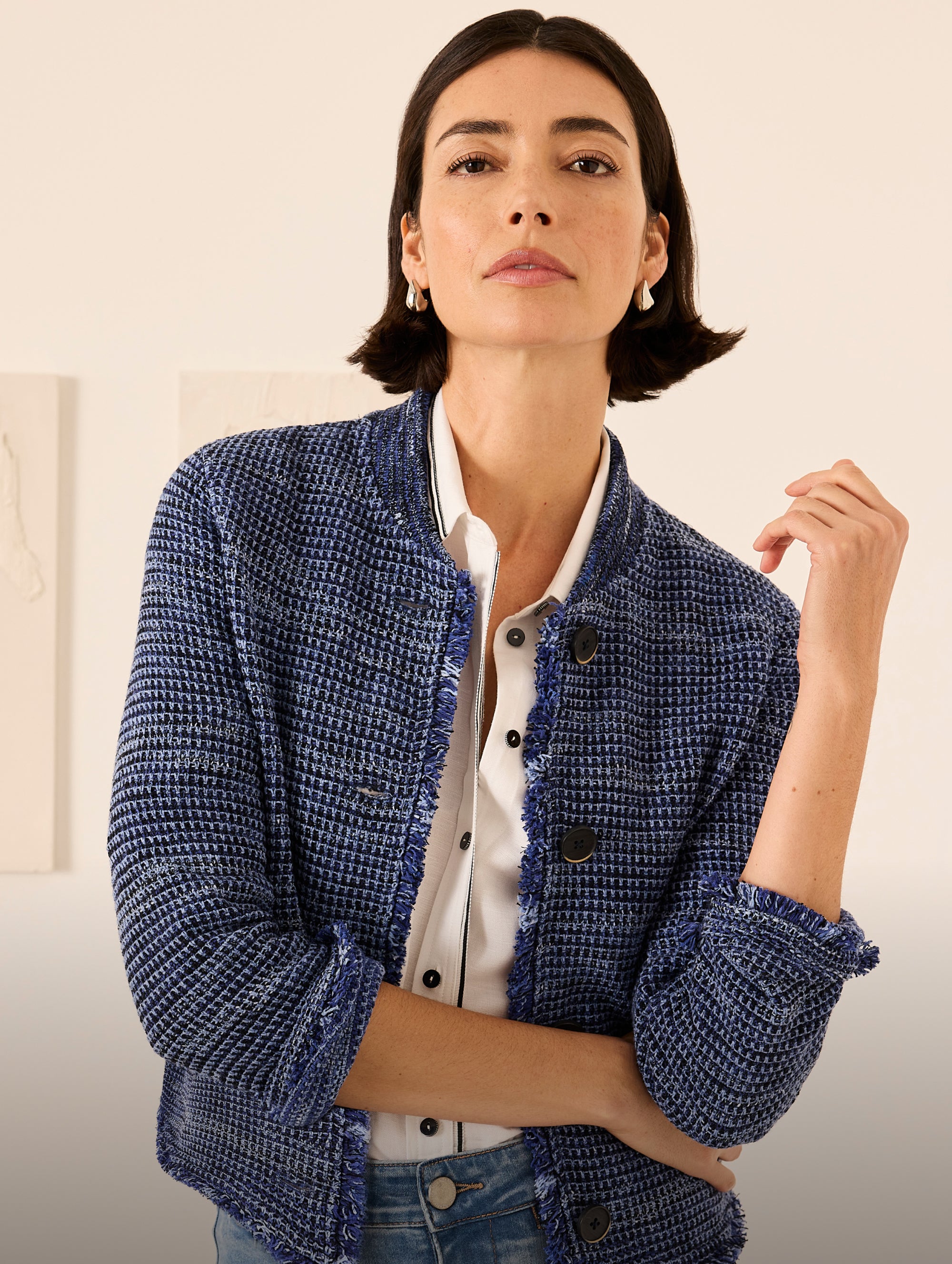 Woman wearing a blue textured blazer over a white shirt with a neutral background