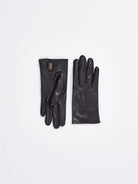 A pair of black lambskin gloves on a white background. One glove shows a short wrist opening with a tan lining.
