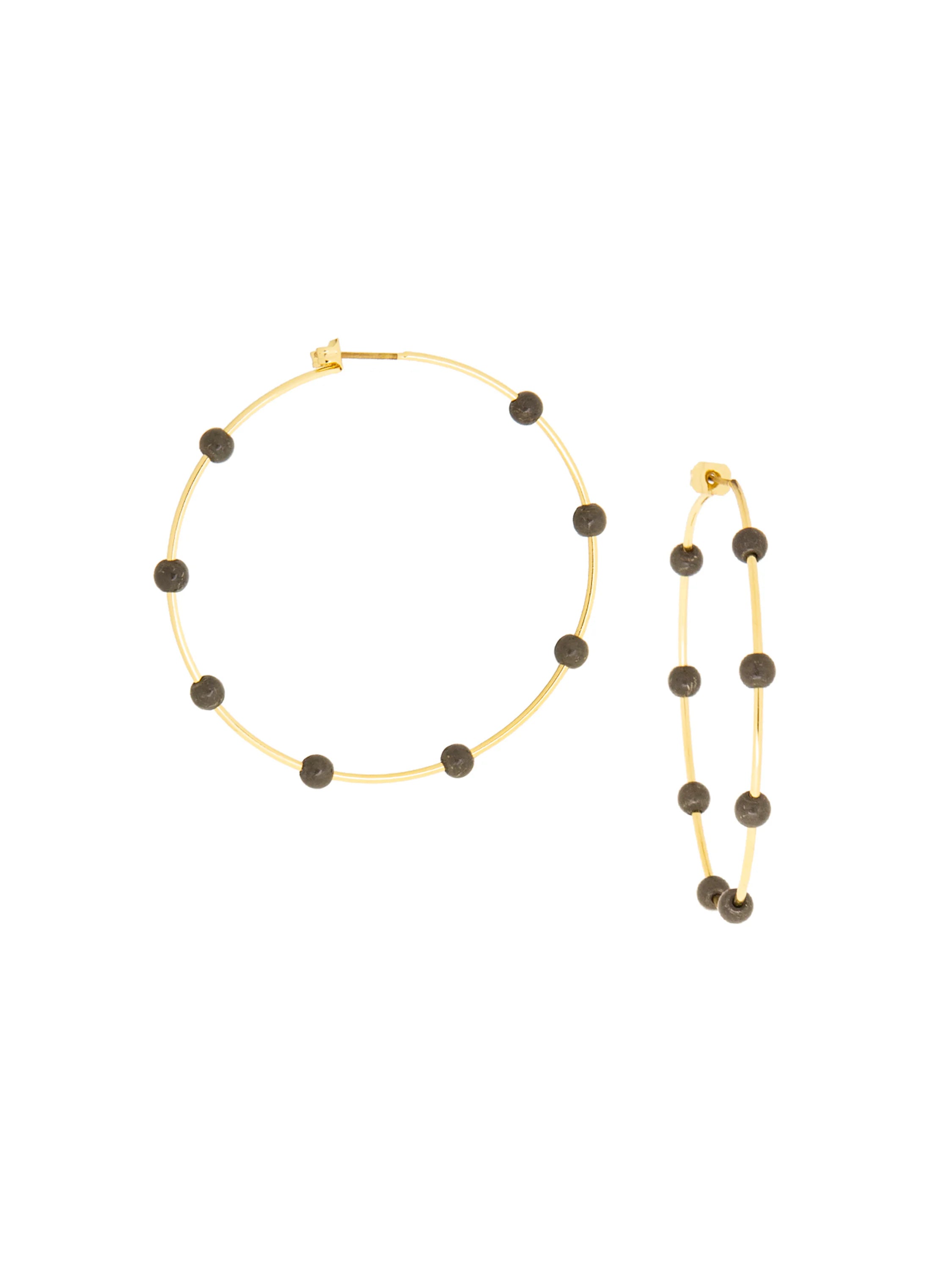 A pair of thin gold hoop earrings with dark, round gems spaced along each hoop.
