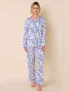 White pajama set with blue monkey, palm tree, and floral print. Button-front long-sleeve top, long pants, blue piping.