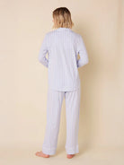 Person from back in light blue long sleeve pajama set with thin white vertical stripes and white piping.