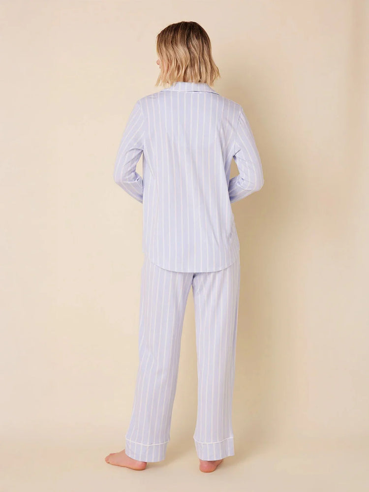 Person from back in light blue long sleeve pajama set with thin white vertical stripes and white piping.