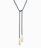 Blue beaded lariat necklace with gold teardrop charms.  The lariat has a knotted center.