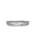 Three-strand stretch bracelet with gray-blue faceted beads, an elongated white pearl, and a gold bead accent.