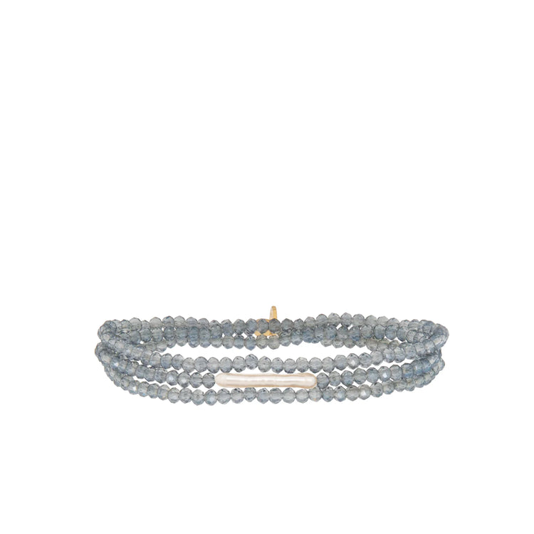 Three-strand stretch bracelet with gray-blue faceted beads, an elongated white pearl, and a gold bead accent.