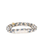Stretch bracelet coiled, with iridescent blue, grey, cream faceted beads, and a long white baroque pearl.