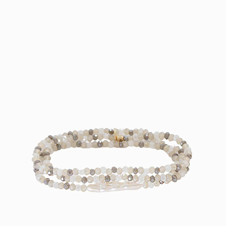 Multi-strand stretch bracelet of small white, beige, & gray faceted beads, with an irregular white pearl & gold clasp.