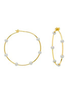 Gold-tone hoop earrings with several evenly spaced white beaded balls. One earring appears larger.