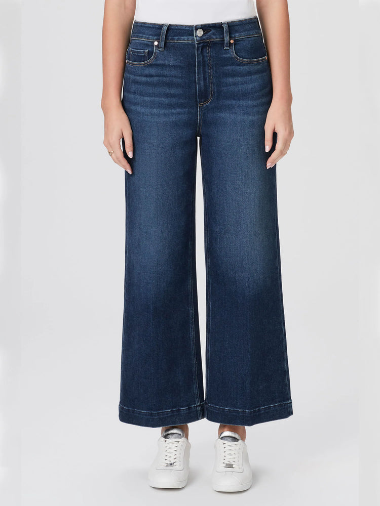 Dark wash, wide-leg jeans with a cropped, cuffed hem.  Shown on a model with white sneakers.
