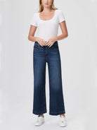 Dark wash, wide-leg jeans; model wears white top & sneakers.