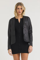 Cropped black faux leather blazer with a tailored fit, notched lapels, and a curved front hem detail.