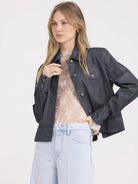 Dark grey faux leather jacket with a pointed collar, two buttoned chest pockets, and large silver buttons.