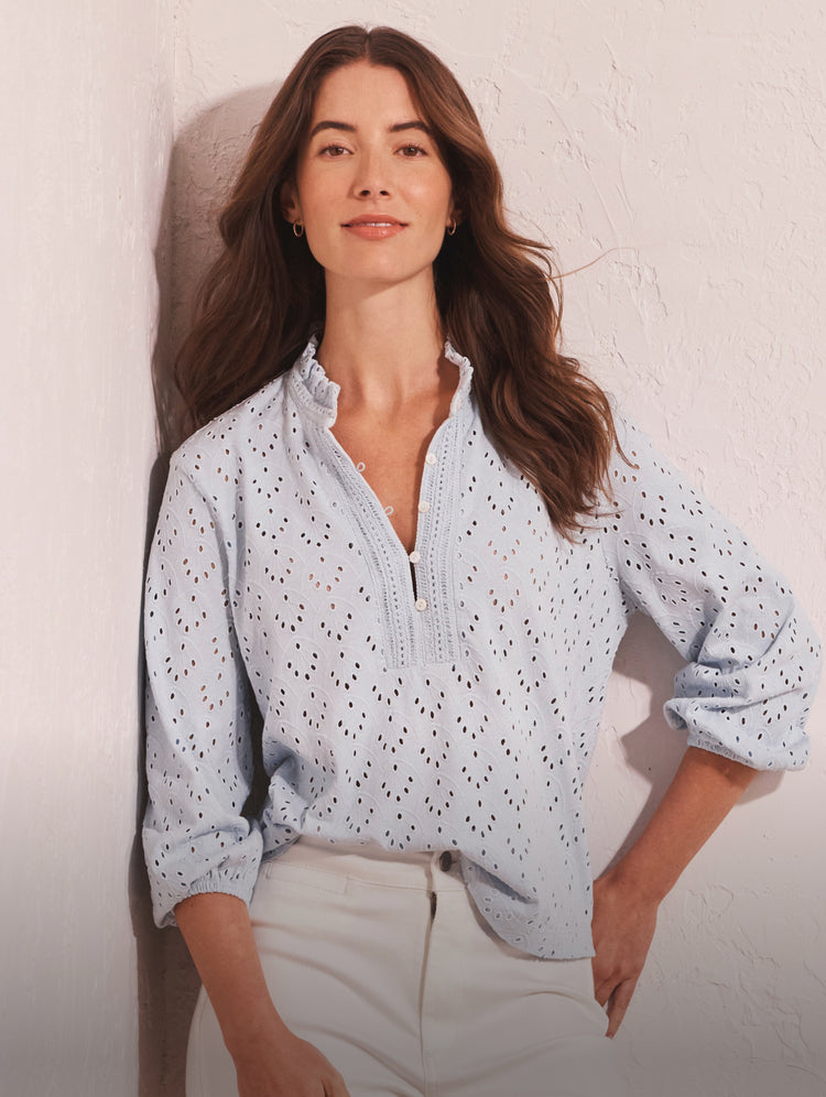 Woman wearing a light blue patterned shirt against a plain background