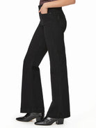 Black high-rise flare jeans shown on model. Fitted through the thigh, flaring out below the knee.
