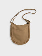 Beige leather hobo bag with adjustable shoulder strap.  Features a small front pocket and subtle stitching.
