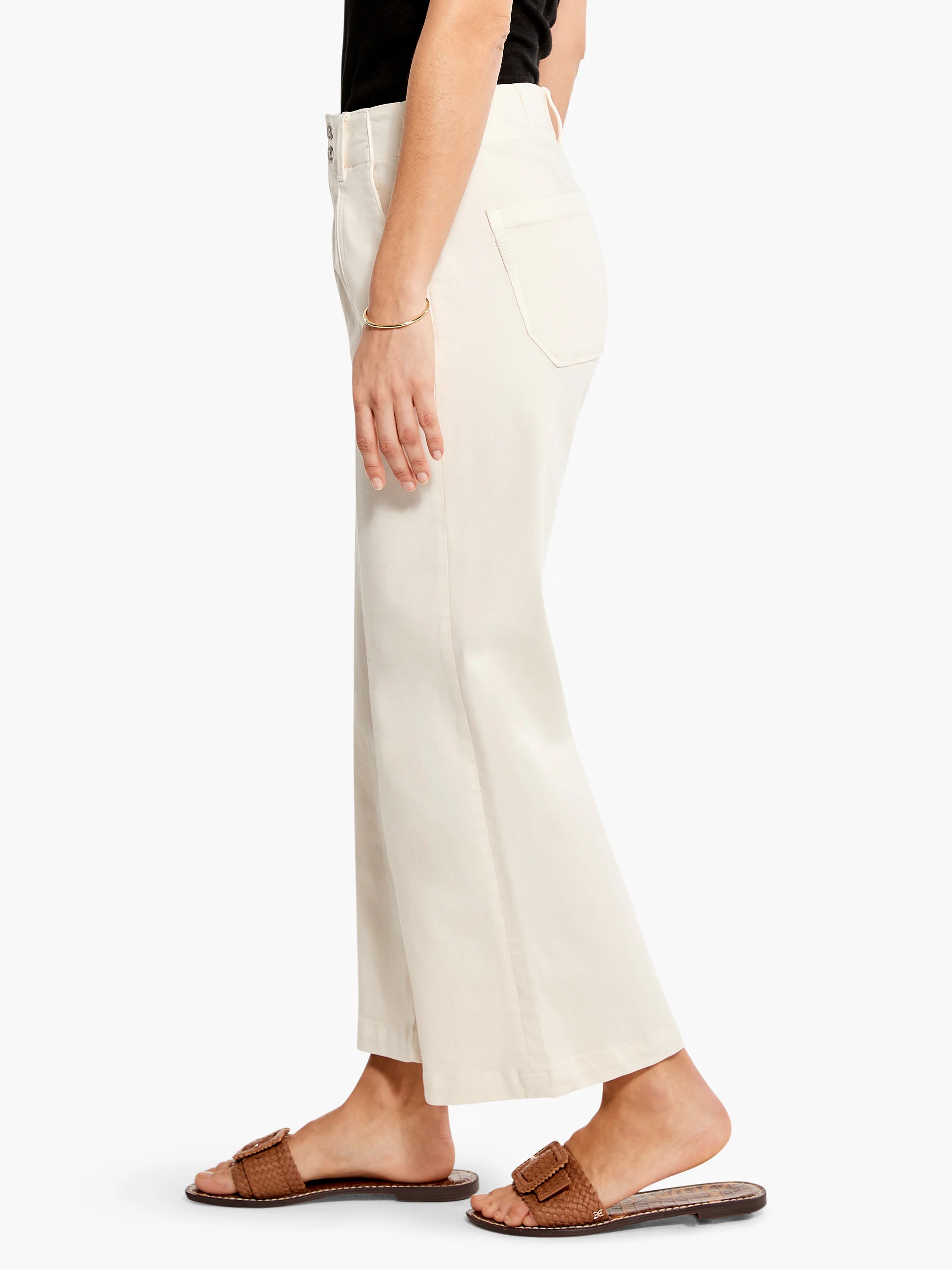 Off-white wide-leg cropped jeans; side view.  Features button fly. Model wears brown sandals.