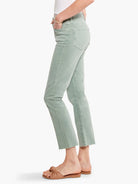 Sage green straight-leg jeans, raw hem, front seams.  Model wears light brown sandals.
