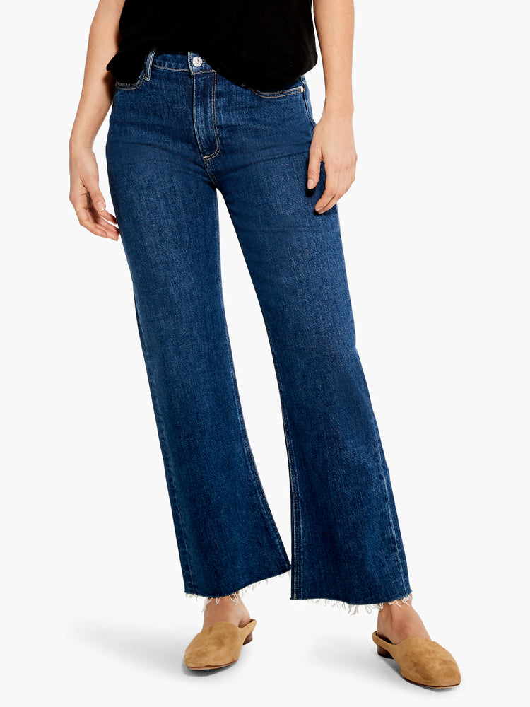Dark wash blue, ankle-length jeans with a slightly flared leg and frayed hem.  Model wears tan mules.