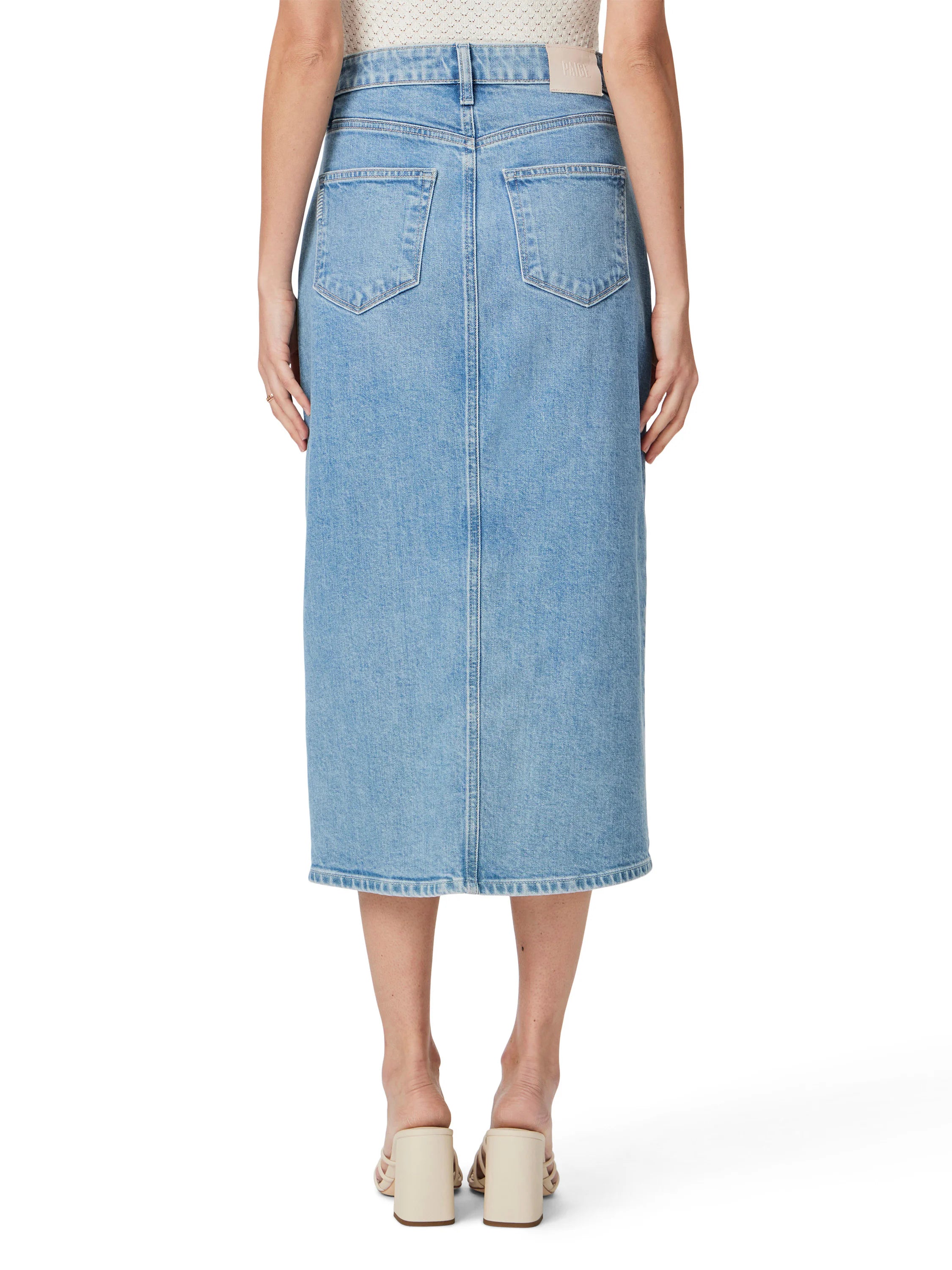 Light wash denim midi skirt, back view. Features two back pockets.  A center back seam is visible.