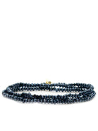 Triple-wrap bracelet with dark-blue faceted beads and small gold clasp.