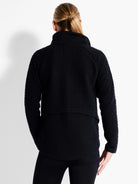 Black quilted jacket with a geometric pattern and stand-up collar, shown from the back.