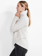 Light beige quilted jacket with a high neck and asymmetric wrap front.