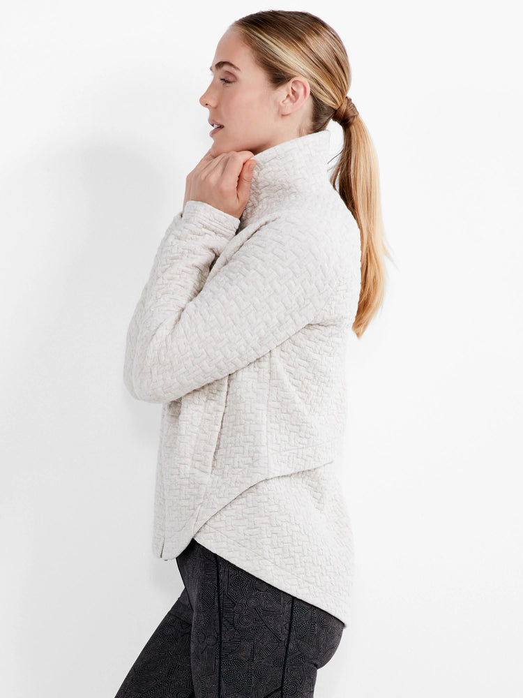 Light beige quilted jacket with a high neck and asymmetric wrap front.