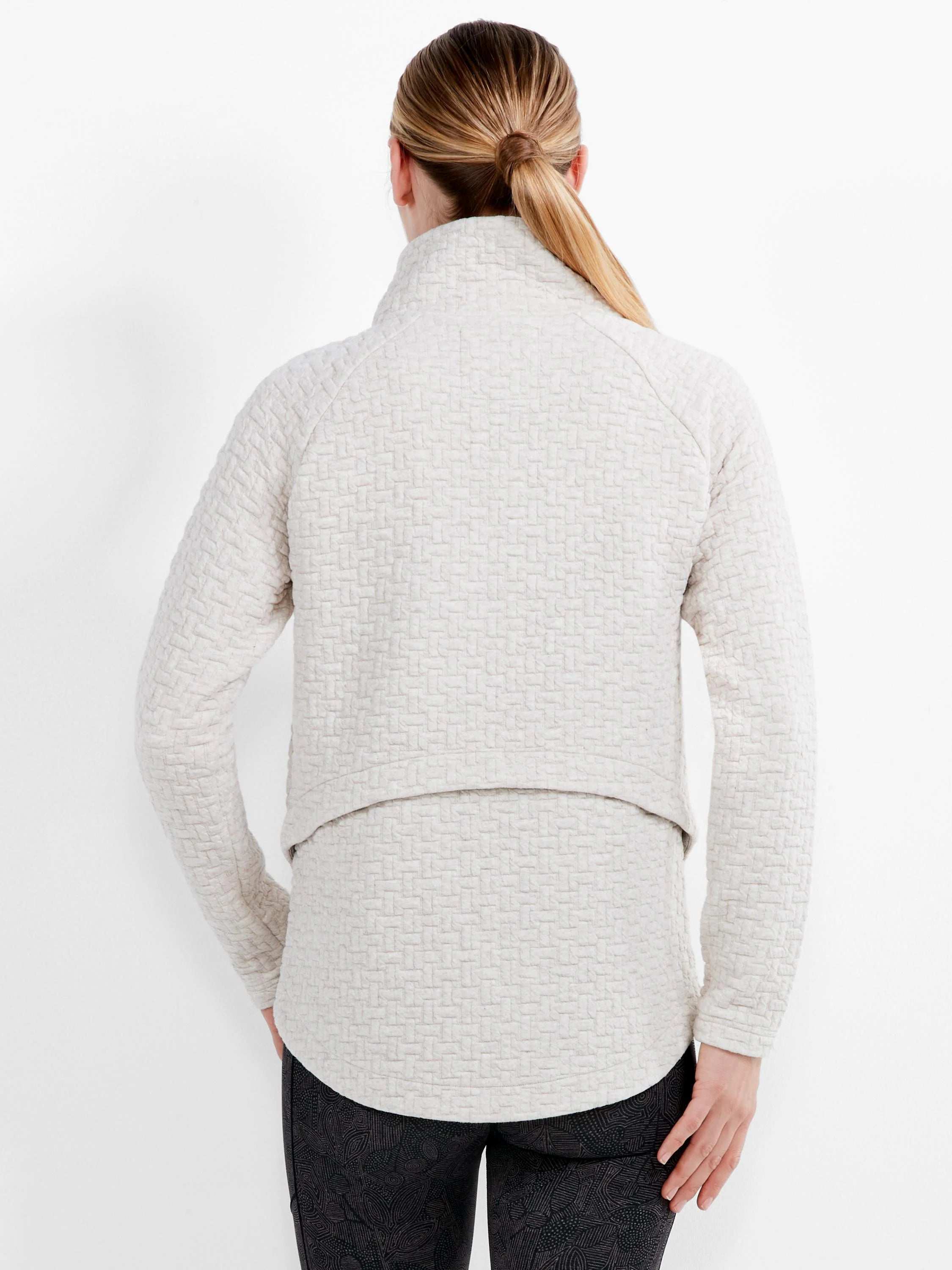 Light cream quilted jacket with a high collar and interlocking geometric pattern.