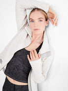 Off-white jacket with an irregular quilted texture, full zipper, and light gray trim on cuffs and collar.