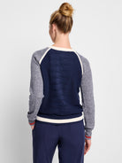 Navy blue sweater with mottled gray sleeves and off-white/cream accents.  Red stripes at cuffs and hem.