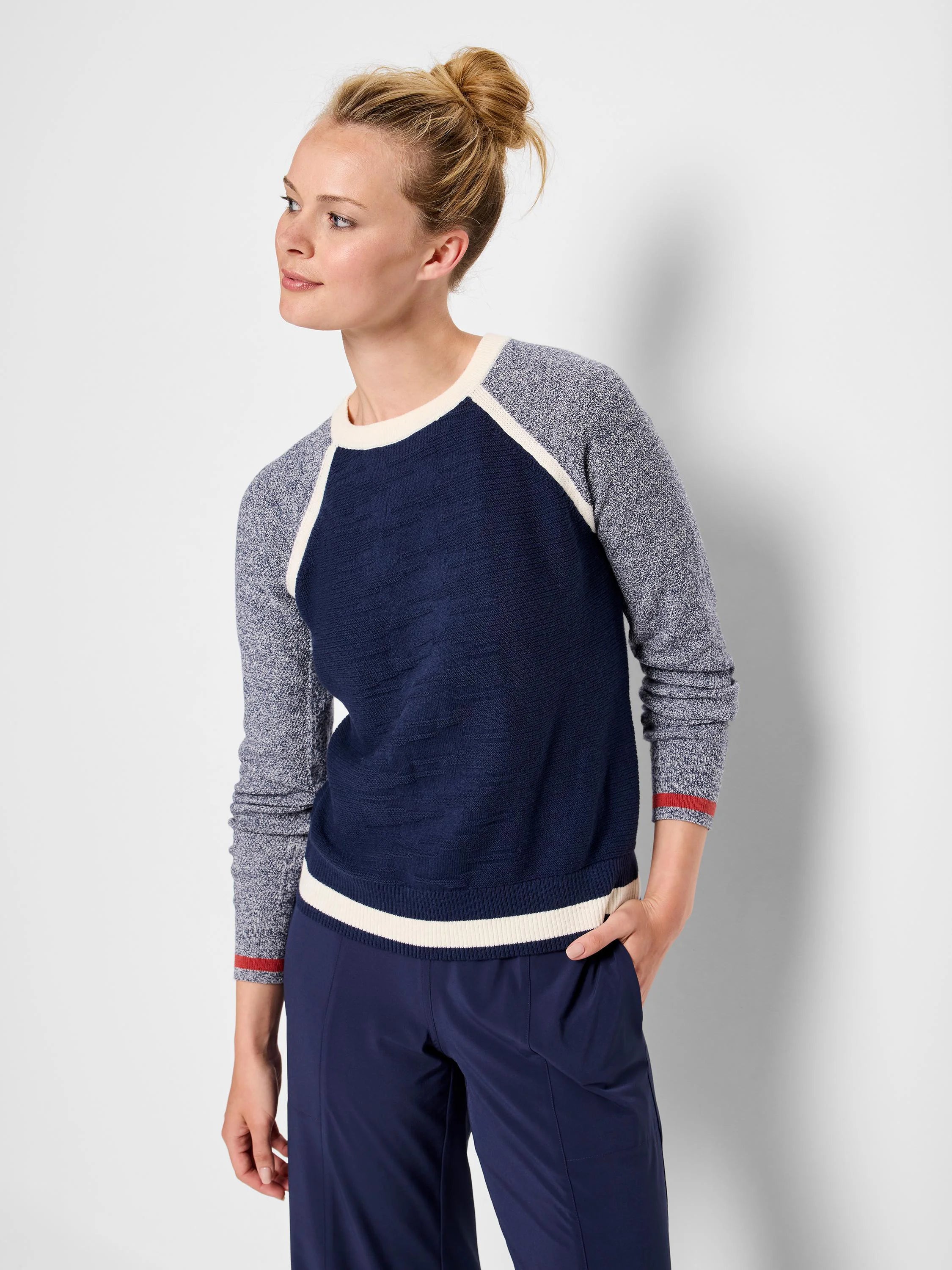 Navy blue sweater with grey speckled sleeves and off-white/cream trim.  Red detail on cuffs.