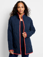 Navy diamond-quilted reversible coat with coral trim along the front opening, collar, cuffs, and snap closure.