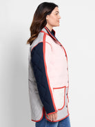 Quilted coat: grey, navy, pink color blocks with red-orange piping, white pocket detail, and front buttons.