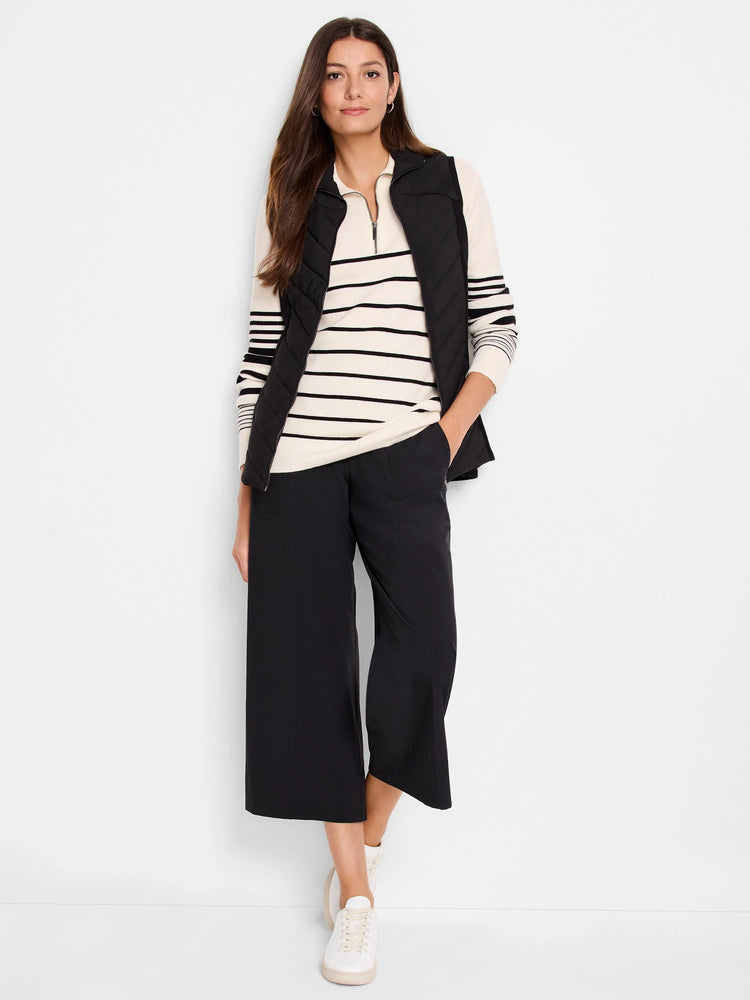 Cream sweater with thin black stripes, layered under a black quilted vest.