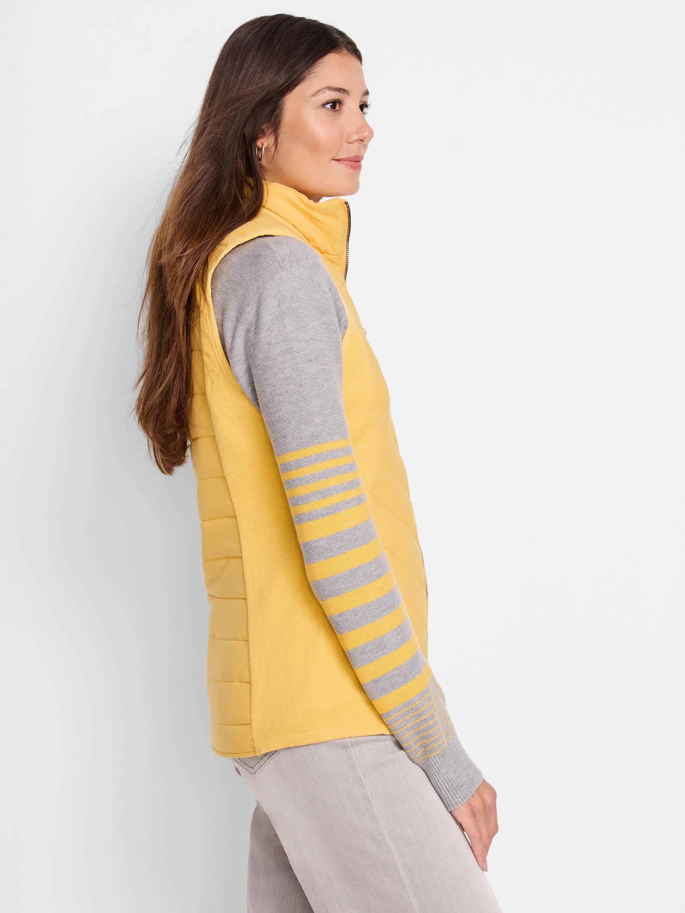 Mustard yellow quilted puffer vest.  Zipper closure.  Shown with gray and mustard striped long sleeve top.