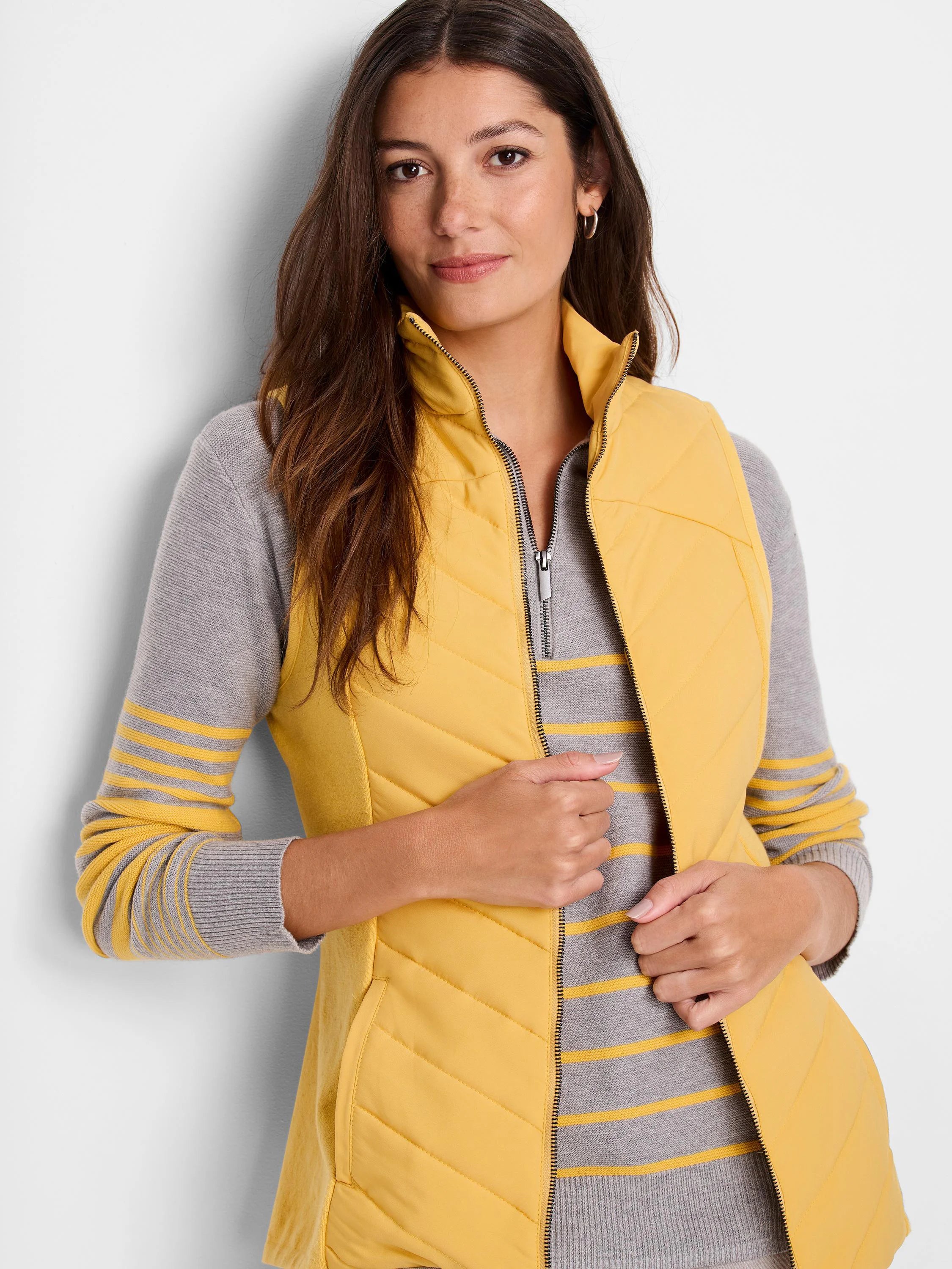 Mustard yellow quilted puffer vest with a zipper.  Gray and yellow striped knit top underneath.