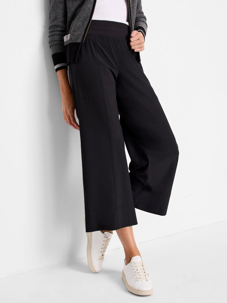 Black wide-leg cropped pants with an elastic waistband. Shown with white sneakers.