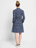 Navy blue dress with a white abstract print, long sleeves, pockets, and a knee-length A-line skirt.