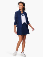 Navy blue jacket with a lace pattern on the sleeves, shown with a white sweater and navy blue skirt.  The model is...
