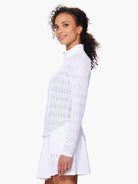 White long-sleeve jacket with a geometric eyelet pattern.  Quarter-zip closure. Shown with white A-line skirt.