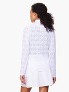 White long-sleeve jacket with repeating chevron and eyelet pattern.  Shown with white A-line mini skirt.