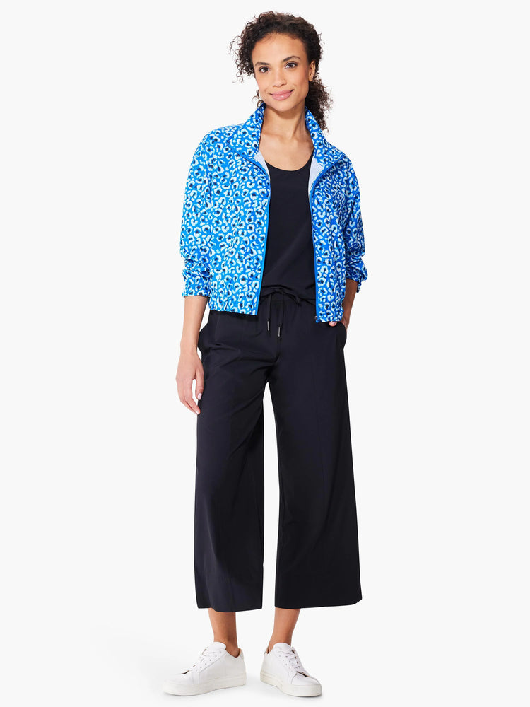 Blue jacket with white leopard print, zip front.  Model also wears black pants and white sneakers.