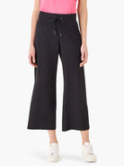 Black wide-leg cropped pants with elastic waistband and drawstring.  Model wears white sneakers.