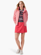 Pink textured zip-up jacket,  multicolored striped shirt, and coral skirt.  Model wears light beige shoes.