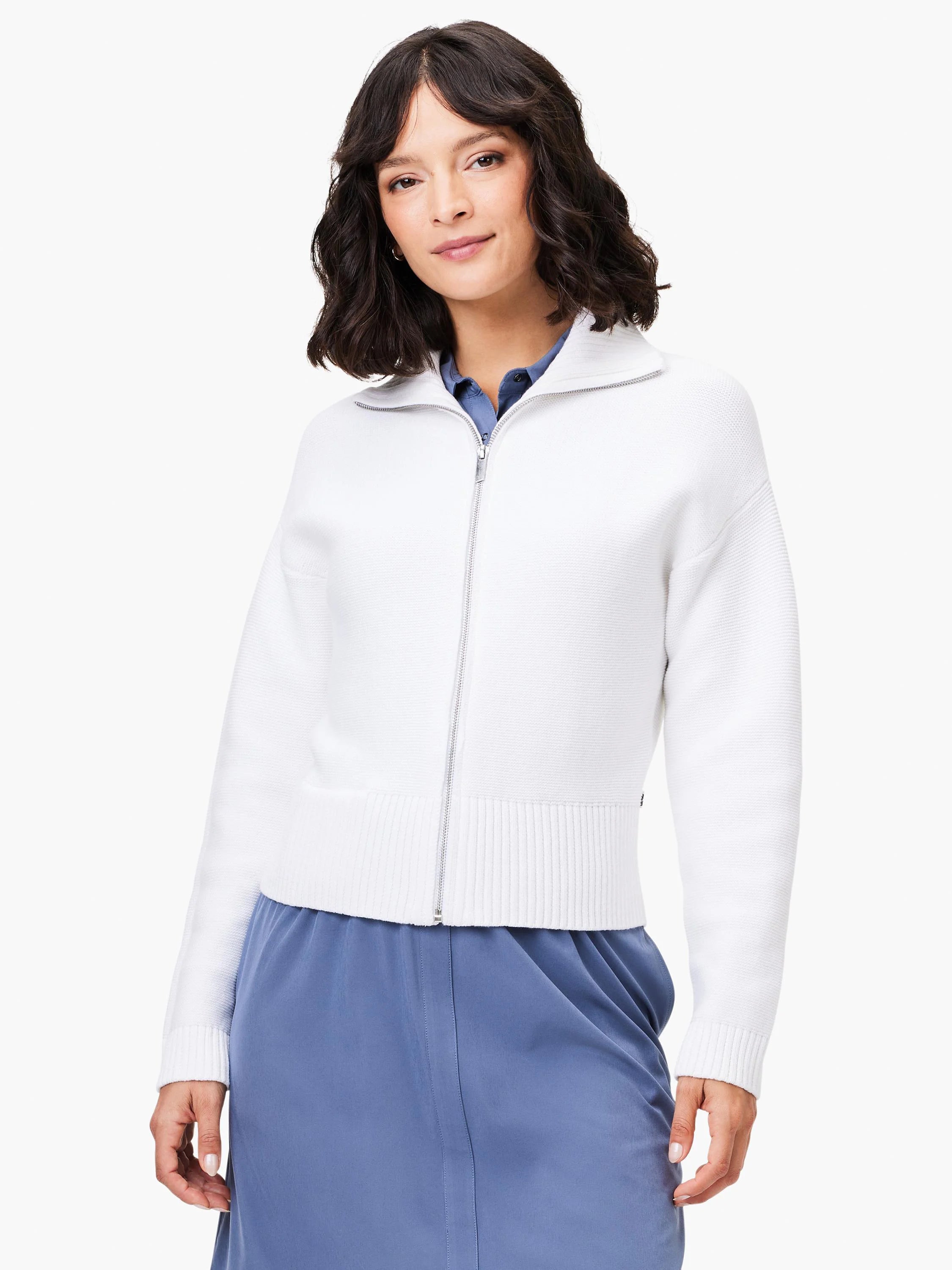 Off-white zip-front sweater jacket with ribbed cuffs and hem.  The model is wearing a blue skirt.