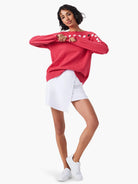 Pink long-sleeve sweater with white and black dotted detail on shoulders and cuffs.